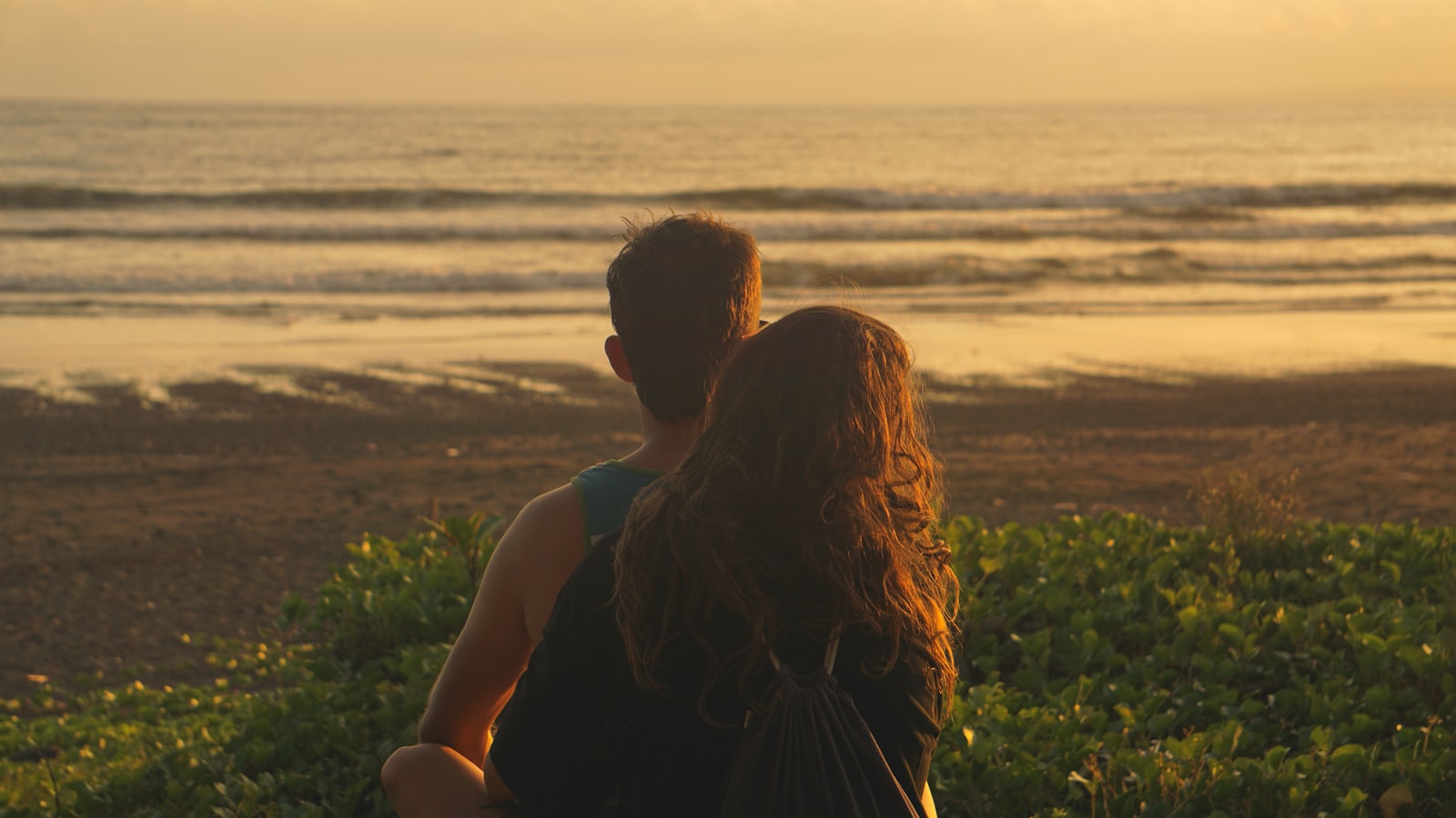 Two travellers watching the sun set over open grassland